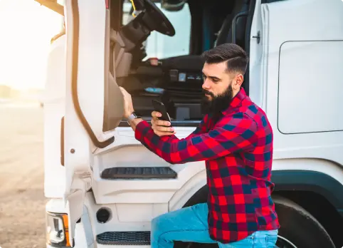 Kierowca ciężarówki korzystający z aplikacji do kontaktu z kierowcą fireTMS Driver