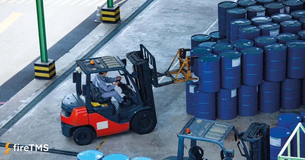 Wózek widłowy transportujący metalowe beczki z niebezpiecznymi materiałami w magazynie