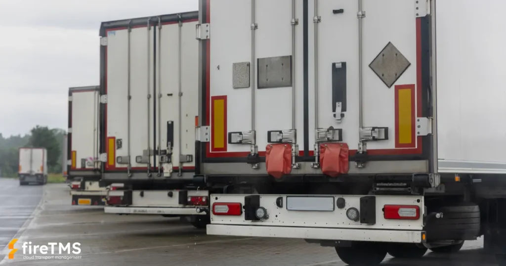 Samochody ciężarowe widziane od tyłu stojące na placu parkingowym w ciemny i deszczowy dzień