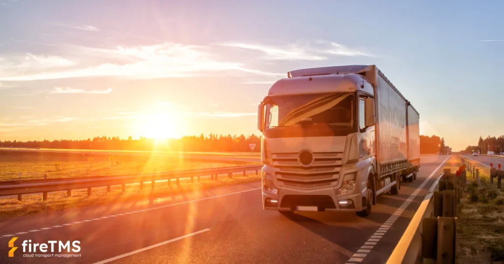 Samochód ciężarowy z przyczepą jedzie autostradą o zachodzie słońca