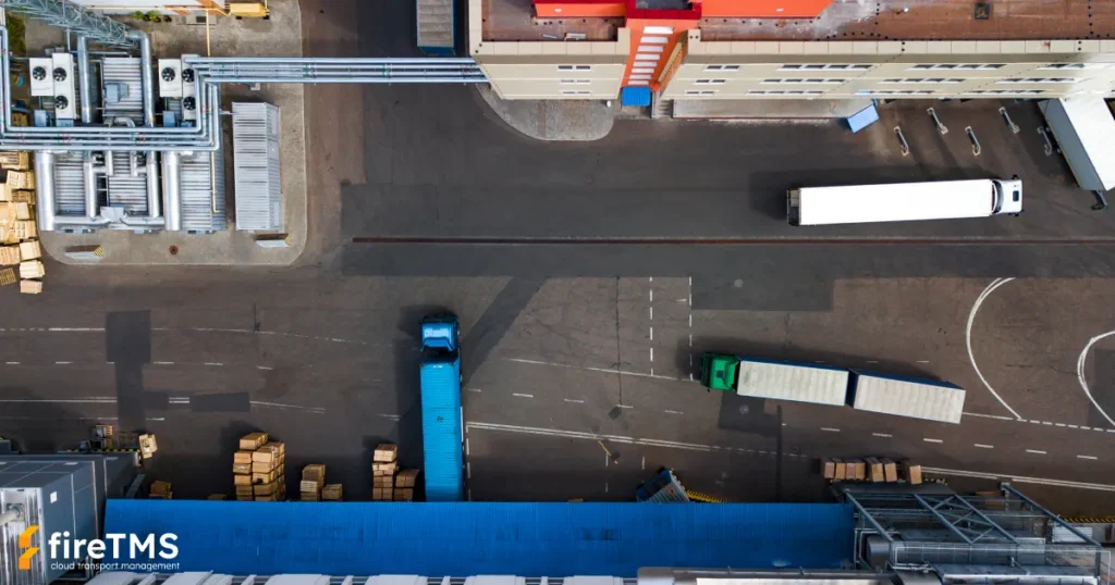 Widziane z góry zestawy transportowe poruszające się w okolicach frontu przeładunkowego w fabryce